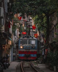 the train is going down the tracks through the narrow alleyway with many buildings on either side