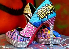 a pair of colorful high heeled shoes sitting on top of a table