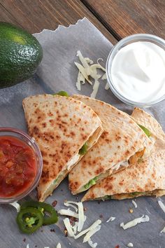 three quesadillas with salsa, sour cream and avocado on the side