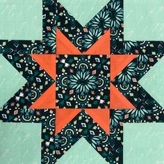 an orange and black star quilted on top of a green surface with white lines