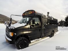 a black truck parked in the snow with trees behind it