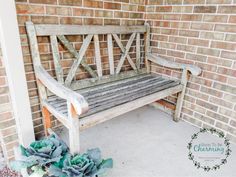 a wooden bench sitting in front of a brick wall next to succulents