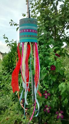 a wind chime hanging from the side of a tree in front of some bushes