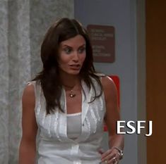 a woman in a white dress standing next to a red door with the words esfj on it