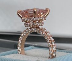 a pink diamond ring sitting on top of a blue box with white diamonds around it