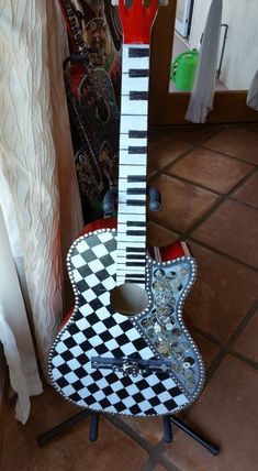 a guitar shaped like a chess board sitting on top of a table next to a wall