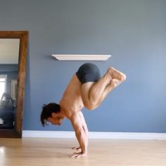 a man is doing a handstand on the floor in front of a mirror