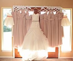 a wedding dress hanging in front of a window