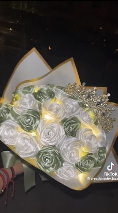 a bouquet of white and green roses is being held up by someone's hand