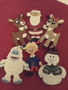 a group of paper cut out animals on a red cloth covered table with santa claus