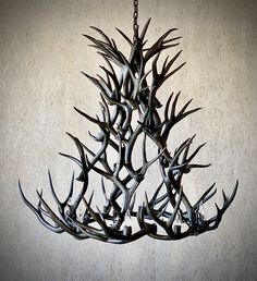 a chandelier made out of antlers hanging from a chain on a wall