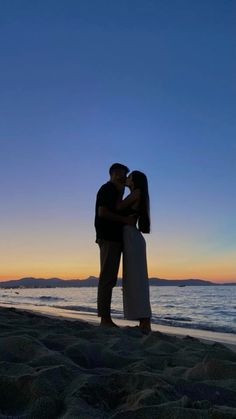 a couple kissing on the beach at sunset