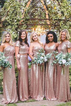 a group of women standing next to each other in front of a gazebo with greenery