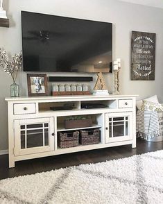 a living room with a large flat screen tv on top of a white entertainment center