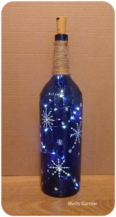 a blue bottle with snowflakes on it is sitting on a wooden table next to a wall