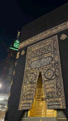 an intricate gold and black building with a clock on it's side at night