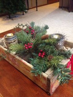 a wooden box filled with pine cones and red berries sitting on top of a table