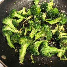 broccoli is being cooked in a wok on the stove top with seasoning sprinkles