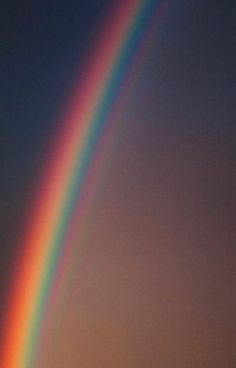 a rainbow appears in the sky over a field