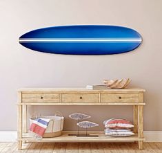 a blue surfboard hanging on the wall above a wooden table