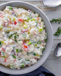 a white bowl filled with macaroni salad on top of a table next to spoons