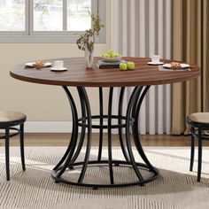 a dining table with two chairs and a vase filled with fruit on top of it