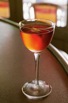 a close up of a wine glass with liquid in it sitting on a table top