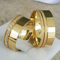 two gold wedding rings sitting on top of each other