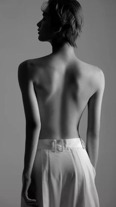 the back of a woman's body is shown in black and white, with her hands on her hips