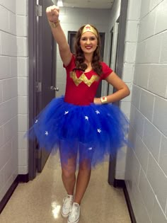 a woman in a red shirt and blue tutu skirt is standing in a hallway