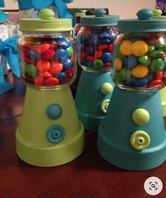 three glass jars filled with candy sitting on top of a wooden table next to each other