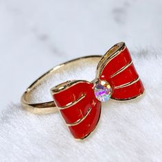 a red bow ring sitting on top of a white blanket with a crystal stone in the center