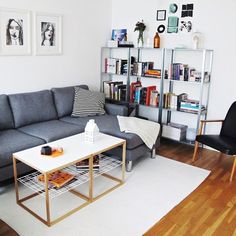 a living room filled with furniture and bookshelves next to a white rug on top of a hard wood floor