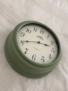 a green clock sitting on top of a white sheet