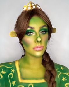 a woman with green and yellow make - up on her face is wearing a crown