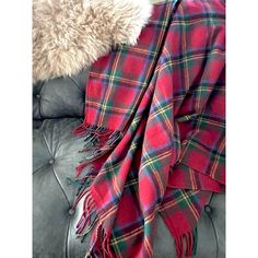 a red and green plaid blanket sitting on top of a leather couch next to a pillow