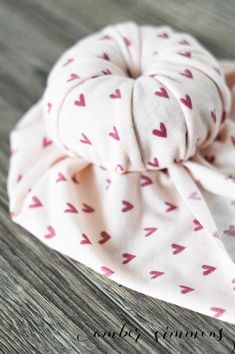 a close up of a bandana on a wooden surface with hearts all over it