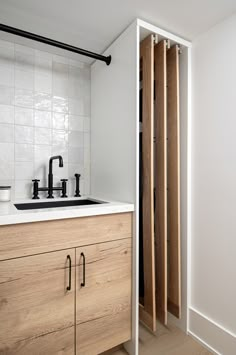 a kitchen with wooden cabinets and white tile backsplash, black faucets