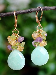 A gorgeous Chrysoprase natural stone, an one-of-a-kind natural gemstone hand-picked for its color and beauty. This lovely pair of earrings features a beautiful Chrysoprase natural stone, with small clusters of amethyst, peridot and citrine gemstones. dangles on a gold ear wire. Each stone may vary slightly in size and shape. Earrings measures 1.75 inches in length. This stunning cluster earrings is unique, feminine and eye-catching, Perfect for anyone that wants to make a statement or to wear to Chrysoprase Gemstone Drop Earrings, Green Multi-stone Dangle Jewelry, Chrysoprase Gemstone Dangle Jewelry, Peacock Pearl, Yellow Citrine, Citrine Gemstone, Green Peridot, Cluster Earrings, Ear Wire