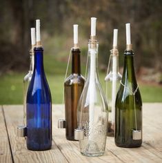 four different colored glass bottles sitting on top of a wooden table next to each other