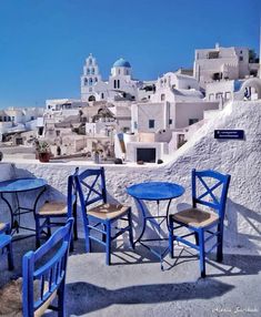 blue chairs and tables on the roof of a building with white buildings in the background