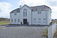 a large white house sitting on top of a gravel road