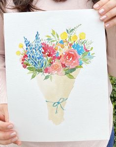 a woman holding up a watercolor painting with flowers in it's bouquets