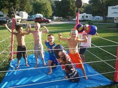 some kids are posing for a picture in front of an obstacle course at a campsite