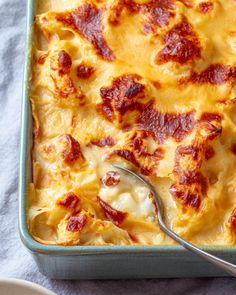 a square casserole dish with cheese and pepperoni on top, next to a fork