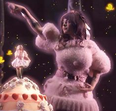 a woman in a dress standing next to a cake