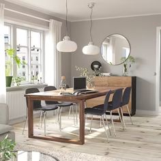 a dining room table with chairs and a laptop computer on it, in front of a window