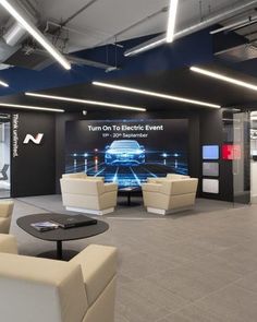 an office lobby with couches, tables and televisions on the wall in front of it