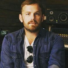 a bearded man sitting in front of sound equipment