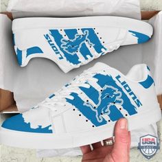 someone is holding up their white and blue sneakers with detroit lions logos on the side